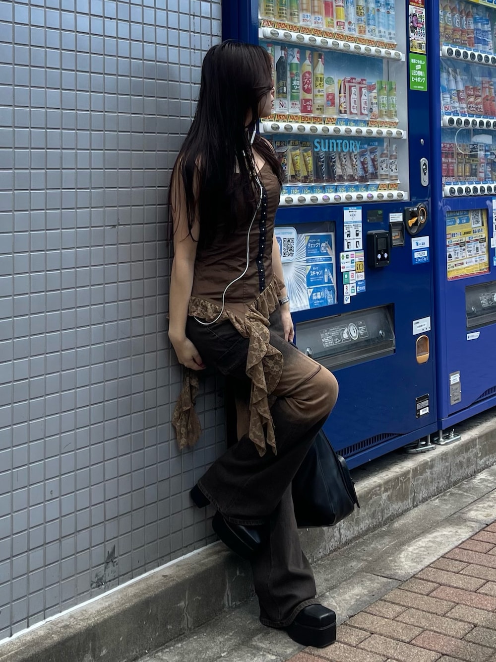 ブラウン系のキャミソール、ブラウン系のデニムパンツ、ブラック系のブーツを着用したレディースの夏コーディネートの3枚目の写真