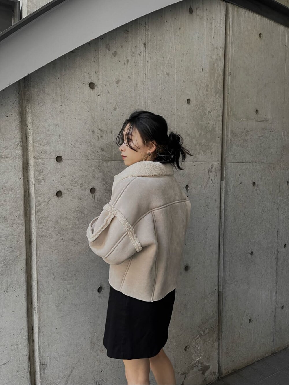 ブラック系のニット/セーター、ブラック系のブーツ、ホワイト系のブルゾンを着用したレディースの冬コーディネートの2枚目の写真