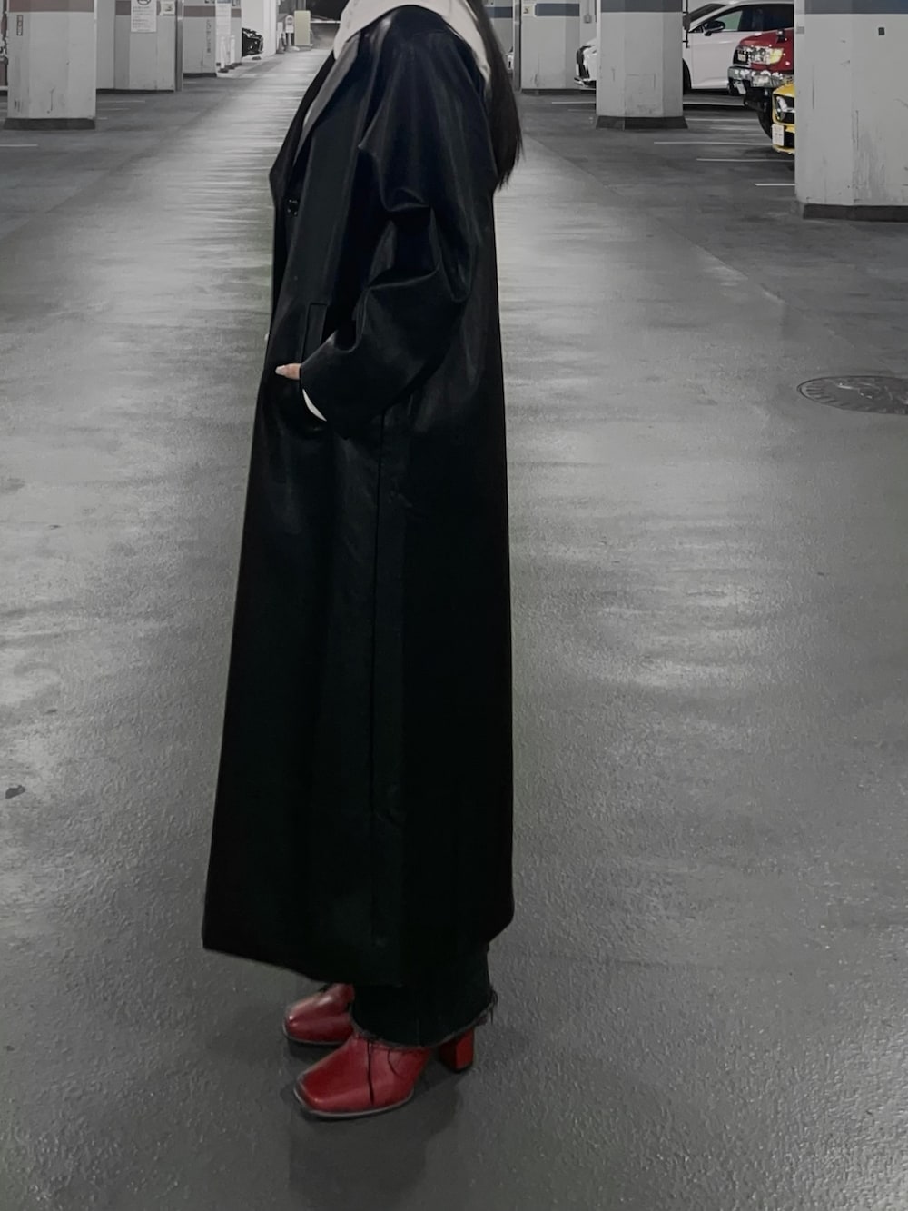 ブラック系のチェスターコート、レッド系のブーツ、ブラック系のデニムパンツを着用したレディースの冬コーディネートの2枚目の写真