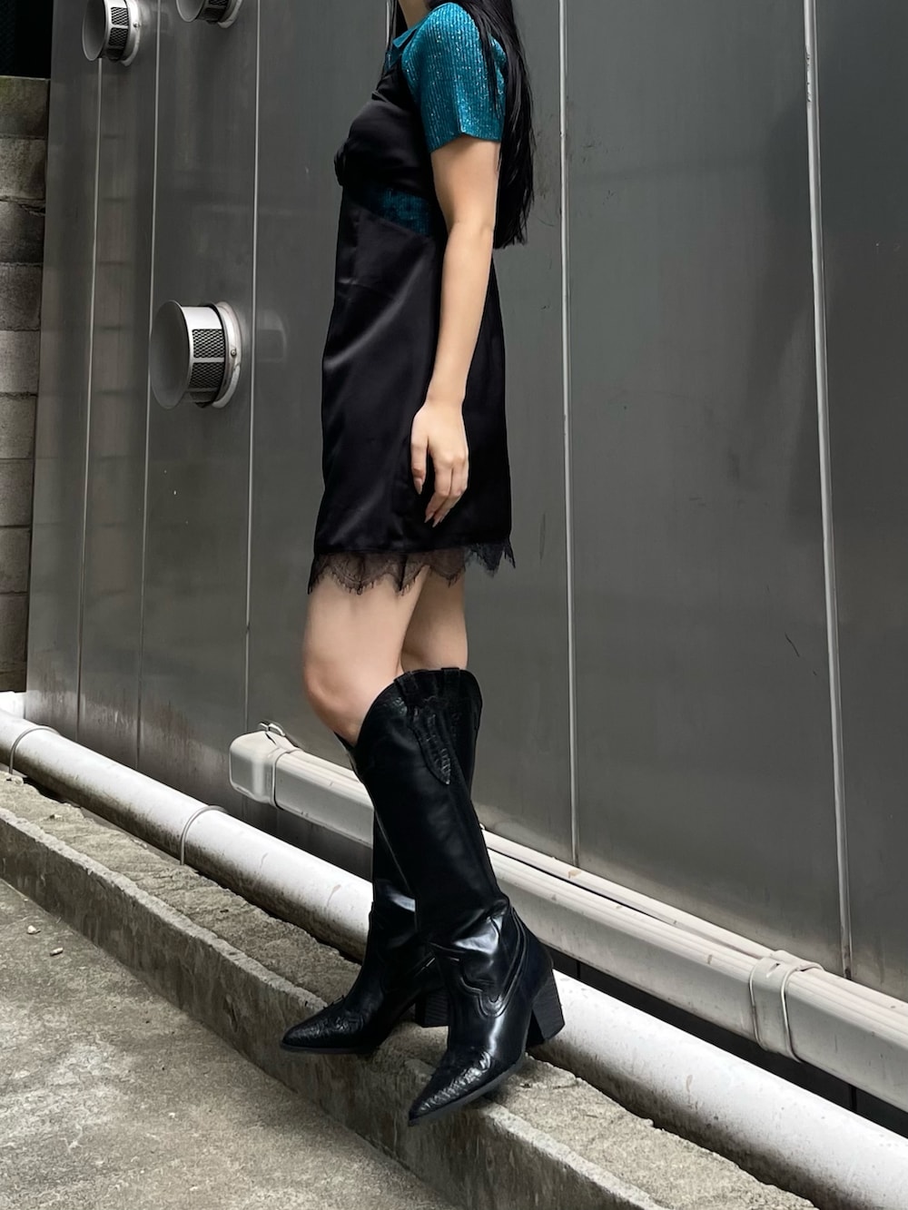 ブルー系のニット/セーター、ブラック系のワンピース、ブラック系のブーツを着用したレディースの夏コーディネートの3枚目の写真