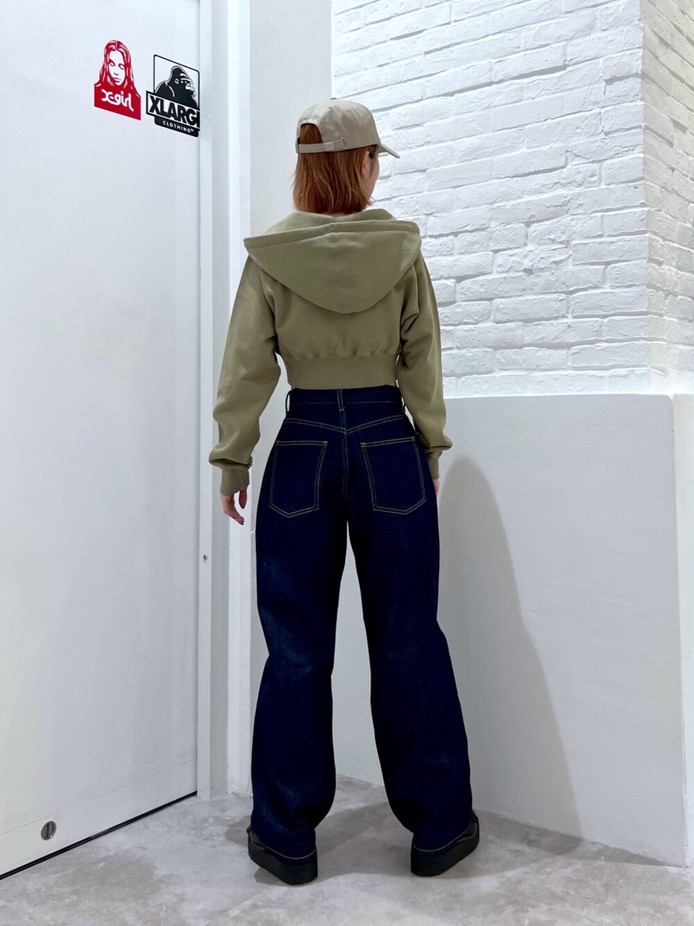 ブルー系のデニムパンツ、グリーン系のパーカー、ベージュ系のキャップを着用したレディースの春コーディネートの2枚目の写真