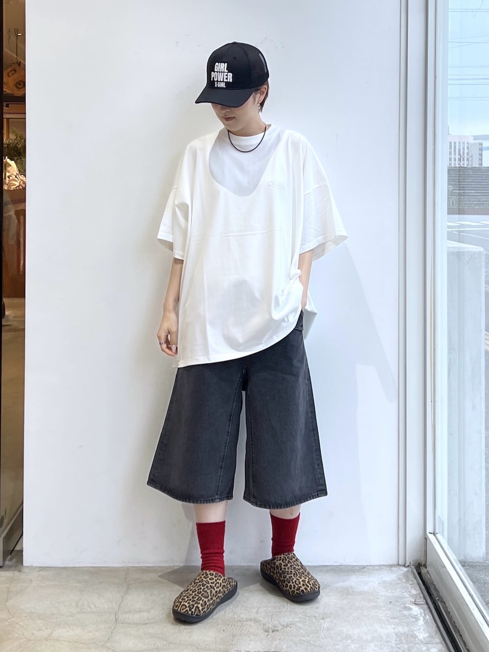 ブラック系のデニムパンツ、ホワイト系のワンピース、ブラック系のキャップを着用したレディースの春コーディネートの2枚目の写真