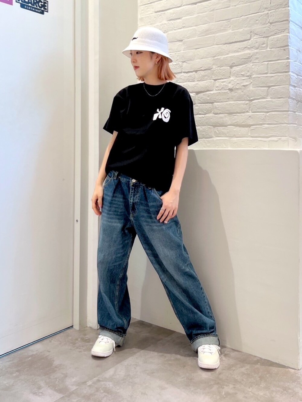 ブルー系のデニムパンツ、ブラック系のTシャツ/カットソー、ホワイト系のハットを着用したレディースの夏コーディネートの2枚目の写真