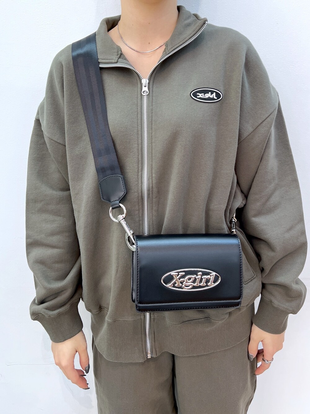 ブラック系のショルダーバッグ、グリーン系のスウェット、グリーン系のスウェットパンツを着用したレディースの冬コーディネートの3枚目の写真