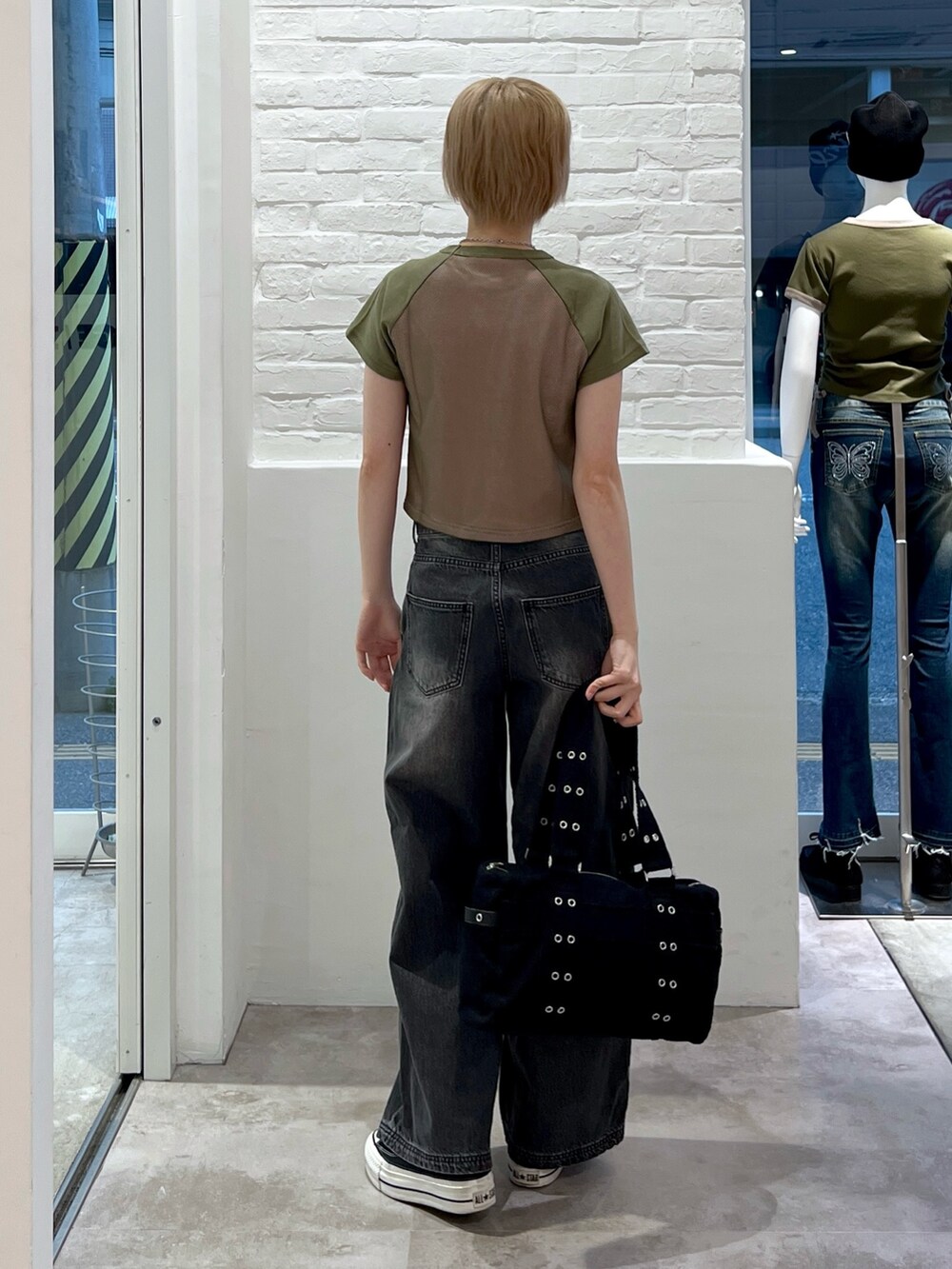 ブラック系のハンドバッグ、ブラック系のデニムパンツ、グリーン系のTシャツ/カットソーを着用したレディースの春コーディネートの2枚目の写真