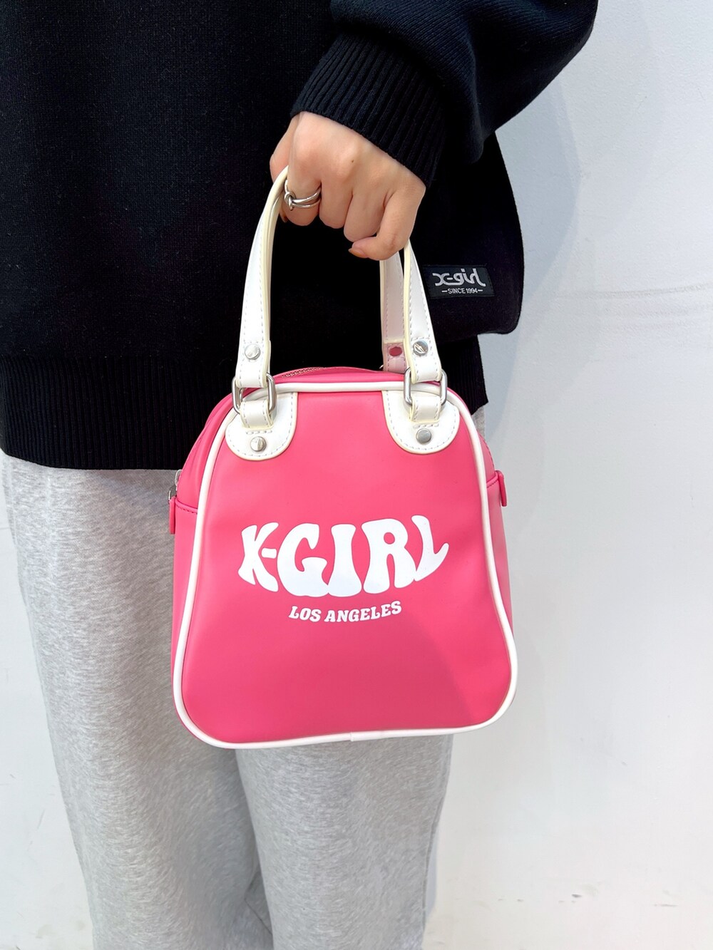 ブラック系のニット/セーター、グレー系のスウェットパンツ、ピンク系のショルダーバッグを着用したレディースの秋コーディネートの6枚目の写真