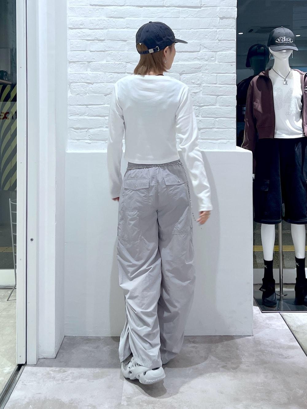 グレー系のカーゴパンツ、ホワイト系のTシャツ/カットソー、ブルー系のキャップを着用したレディースの秋コーディネートの2枚目の写真