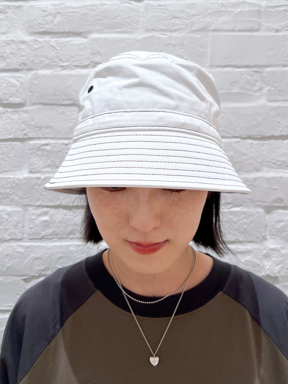 グリーン系のワンピース、グレー系のショルダーバッグ、ホワイト系のハットを着用したレディースの夏コーディネートの5枚目の写真