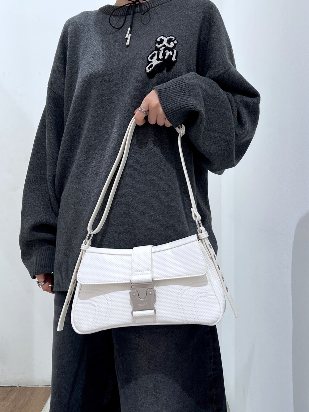 ホワイト系のショルダーバッグ、ブラック系のデニムパンツ、グレー系のニット/セーターを着用したレディースの秋コーディネートの5枚目の写真