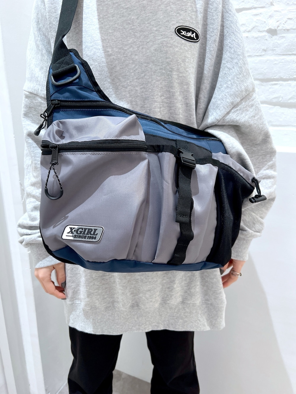 グレー系のスウェット、ブラック系のデニムパンツ、ブルー系のショルダーバッグを着用したレディースの春コーディネートの6枚目の写真