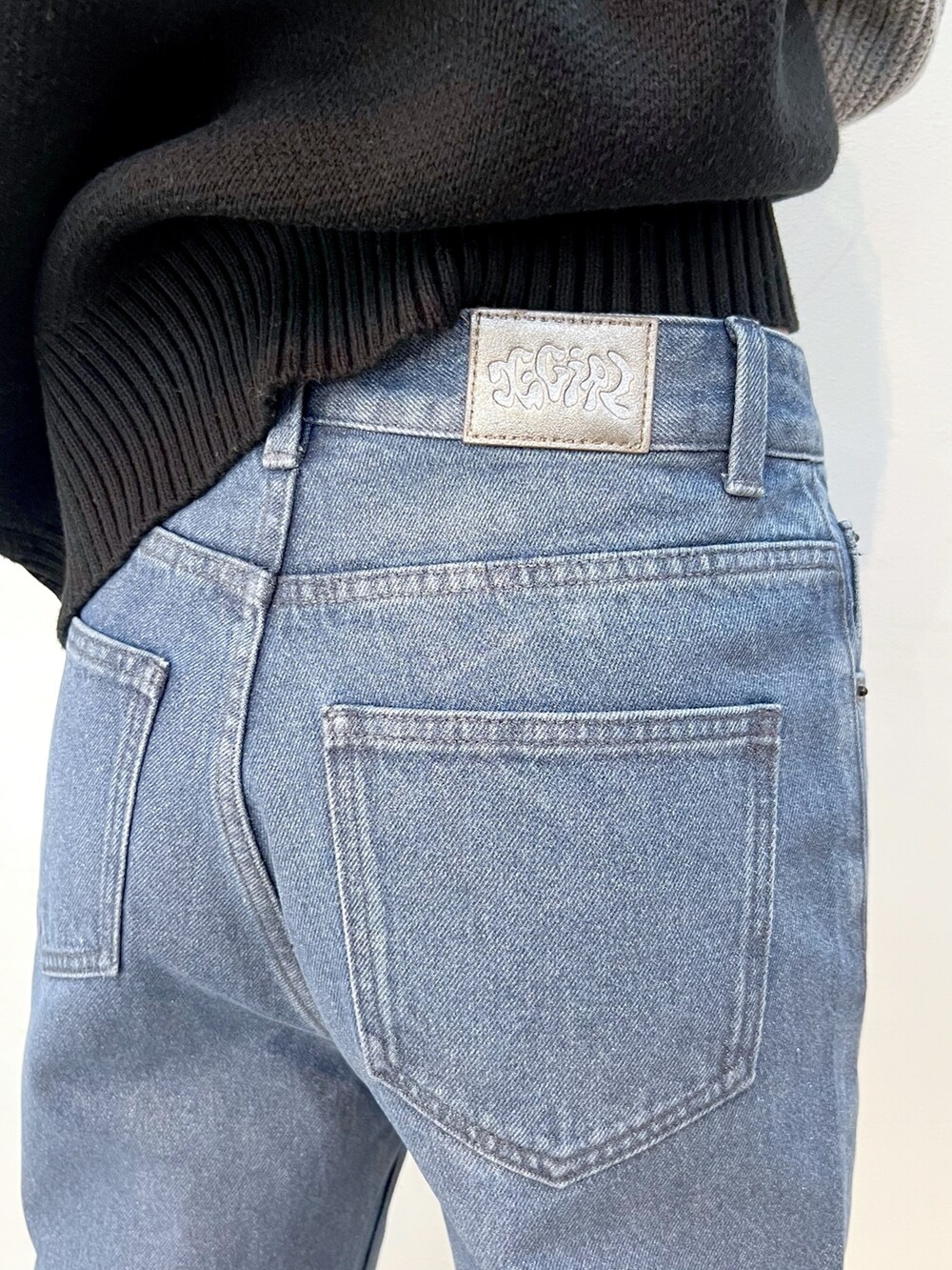 ブルー系のデニムパンツ、ブラック系のニット/セーター、ブラック系のニットキャップ/ビーニーを着用したレディースの秋コーディネートの7枚目の写真