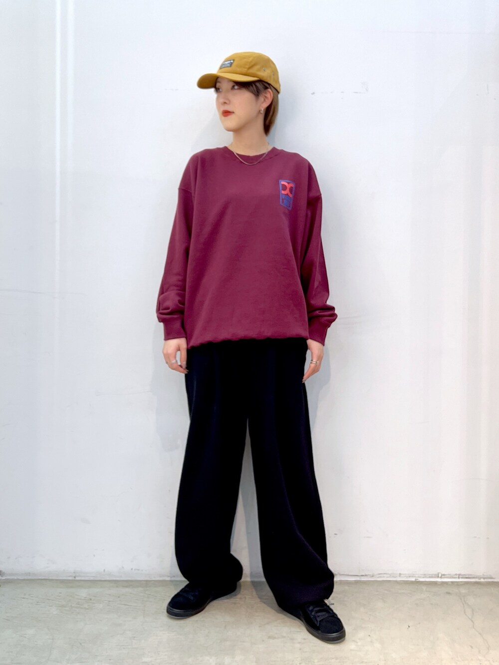 レッド系のスウェット、ブラック系のスウェットパンツ、ブラック系のスニーカーを着用したレディースの秋コーディネートの2枚目の写真