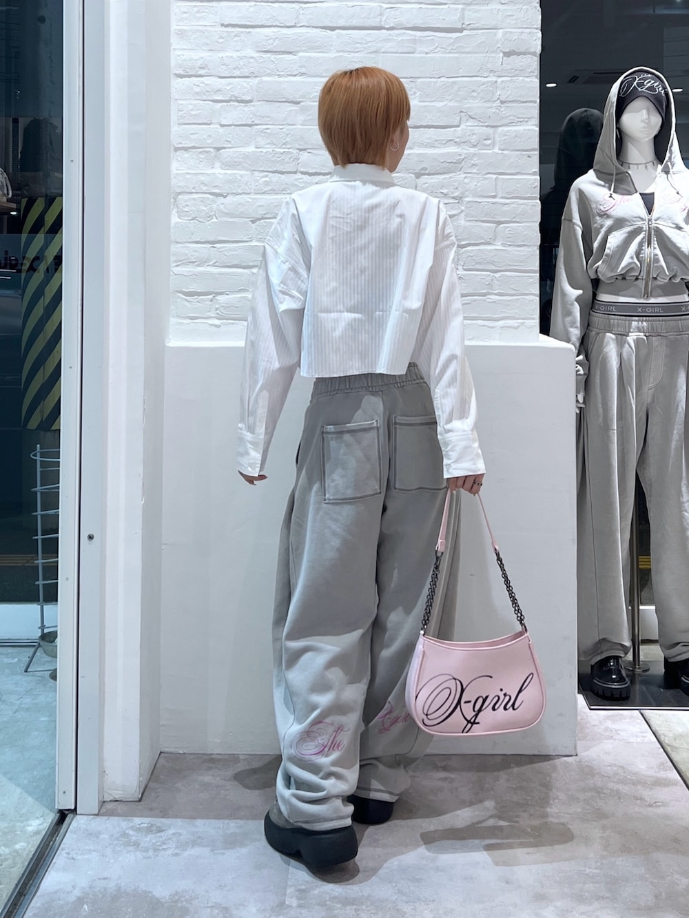 ピンク系のショルダーバッグ、グレー系のスウェットパンツ、ホワイト系のシャツ/ブラウスを着用したレディースの春コーディネートの2枚目の写真