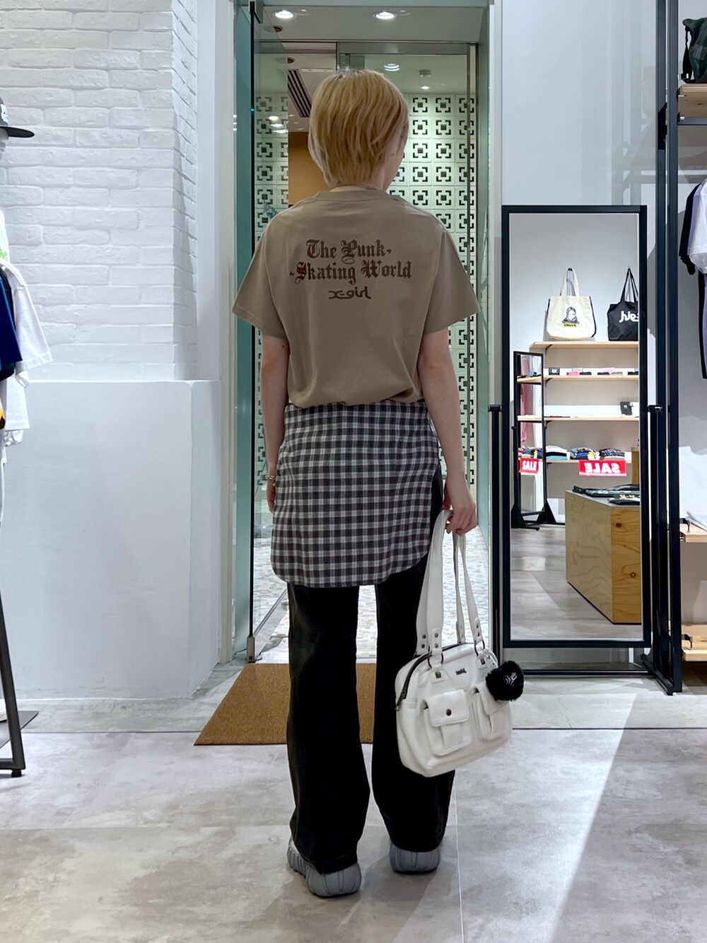 ブラック系のデニムパンツ、ホワイト系のハンドバッグ、ブラック系のシャツ/ブラウスを着用したレディースの夏コーディネートの2枚目の写真