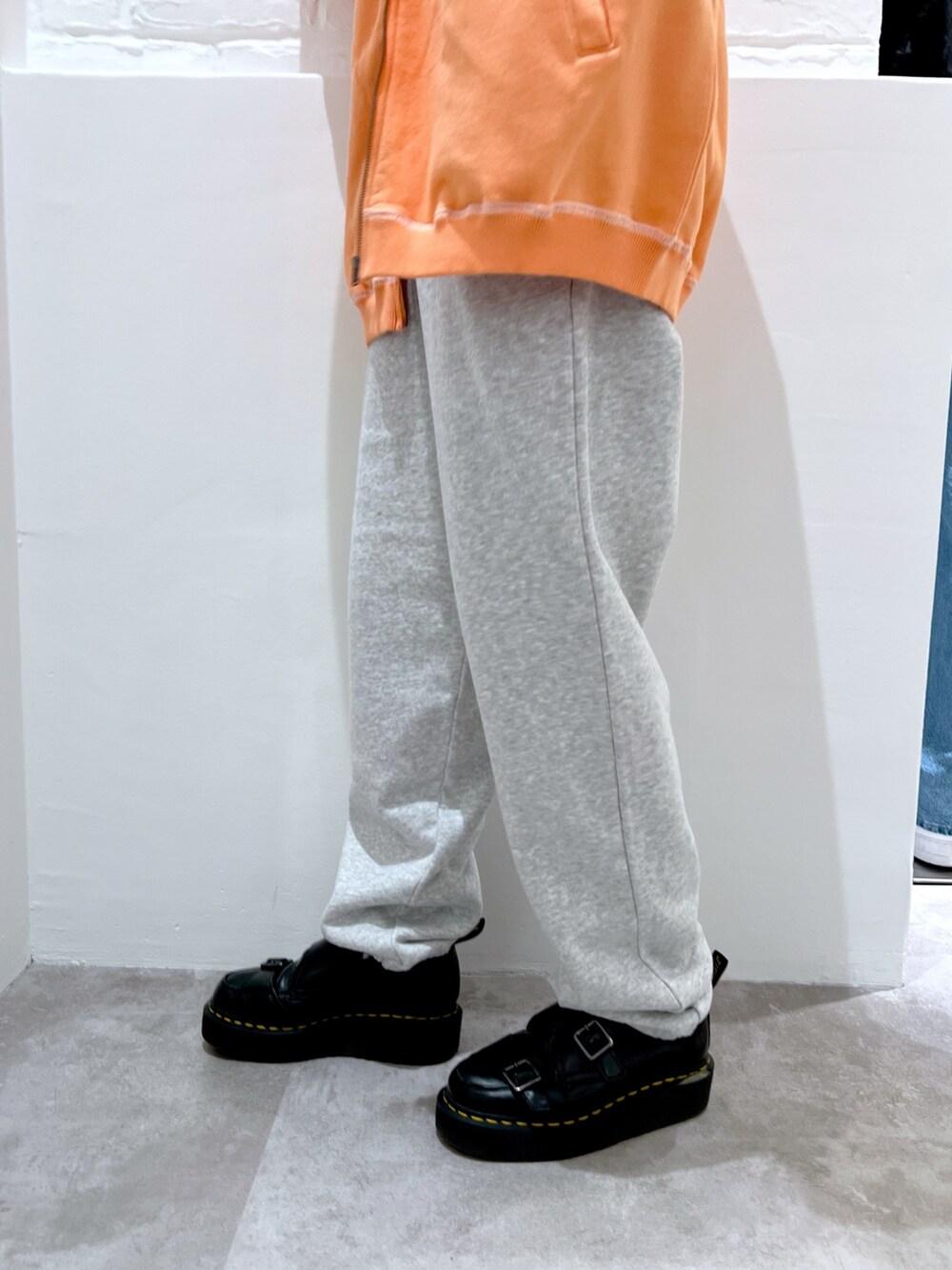 グレー系のスウェットパンツ、オレンジ系のスウェット、ホワイト系のパーカーを着用したレディースの春コーディネートの5枚目の写真