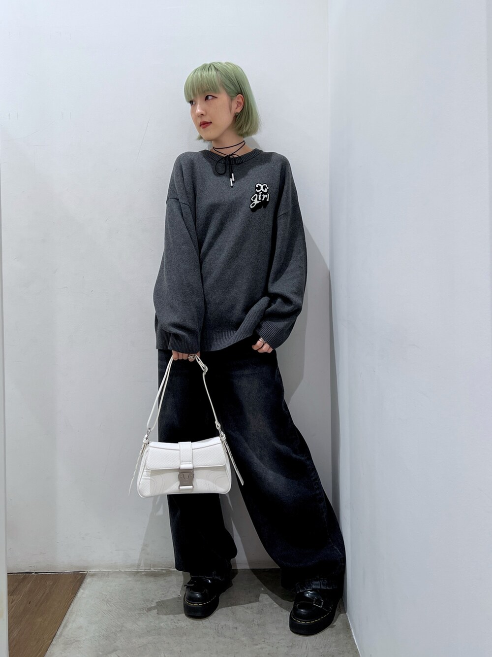 ホワイト系のショルダーバッグ、ブラック系のデニムパンツ、グレー系のニット/セーターを着用したレディースの秋コーディネートの2枚目の写真