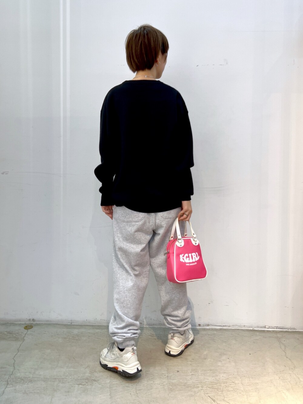 ブラック系のニット/セーター、グレー系のスウェットパンツ、ピンク系のショルダーバッグを着用したレディースの秋コーディネートの2枚目の写真