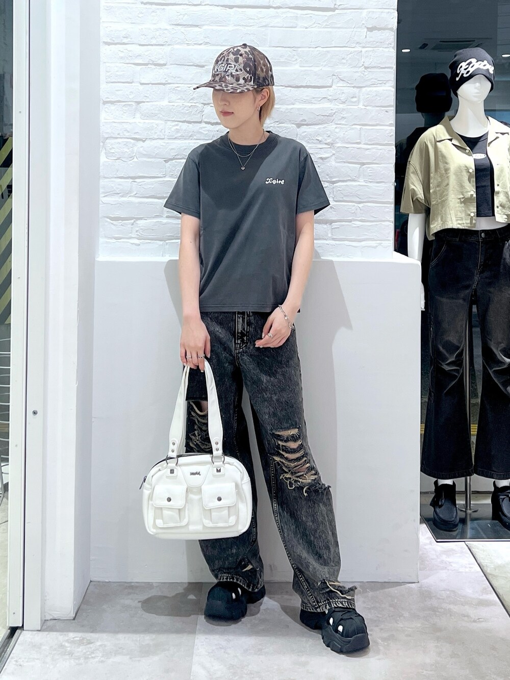 ブラック系のデニムパンツ、ホワイト系のハンドバッグ、ブラック系のTシャツ/カットソーを着用したレディースの夏コーディネートの2枚目の写真