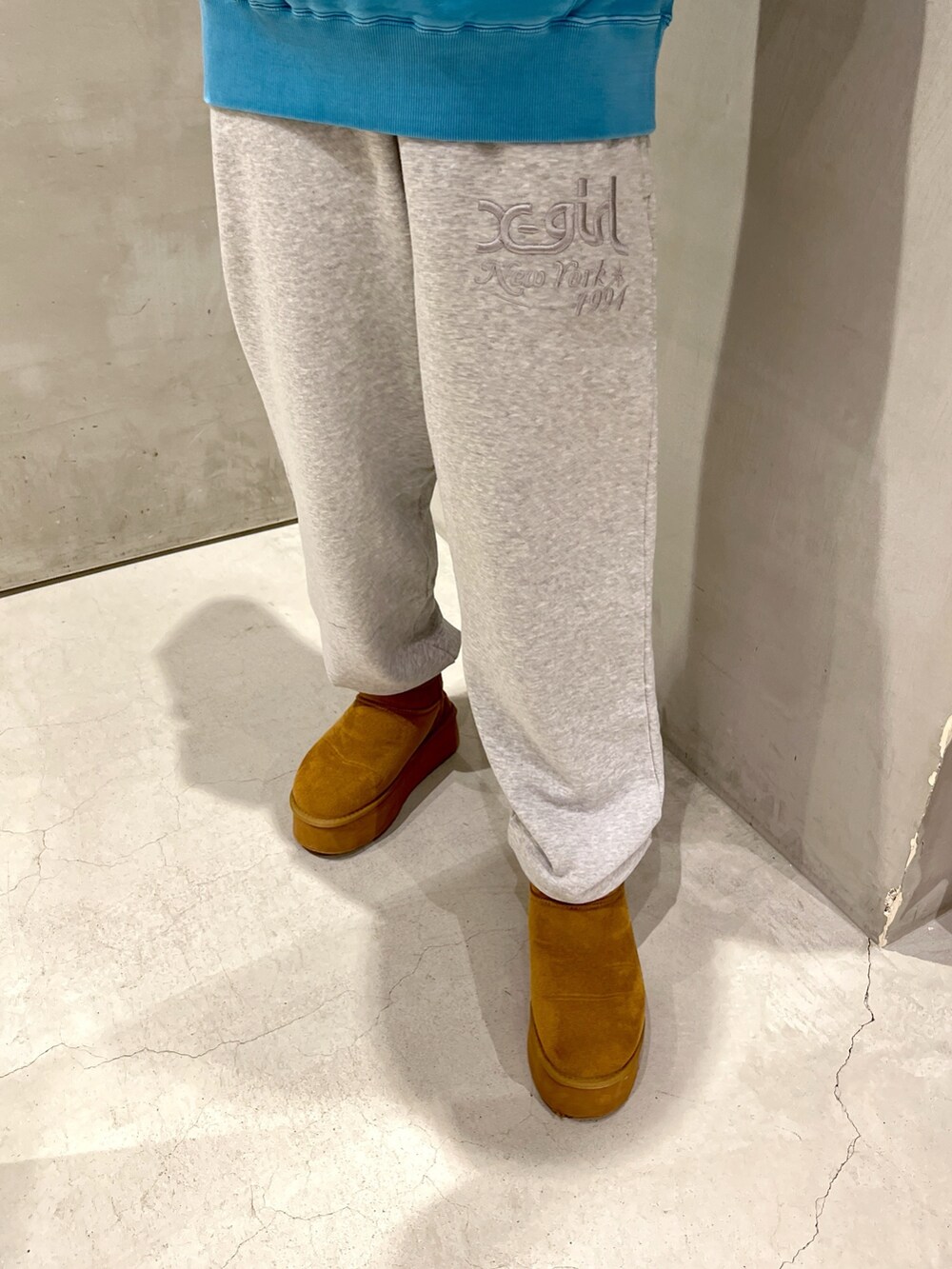 ブルー系のパーカー、ブラック系のショルダーバッグ、グレー系のスウェットパンツを着用したレディースの秋コーディネートの4枚目の写真