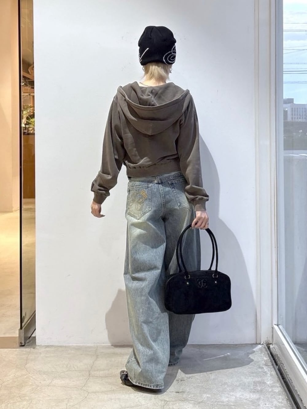 ブラウン系のパーカー、ブルー系のデニムパンツ、ブラック系のハンドバッグを着用したレディースの夏コーディネートの2枚目の写真