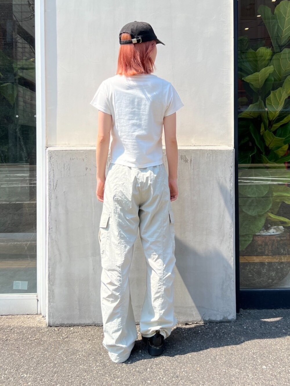 グレー系のカーゴパンツ、ホワイト系のTシャツ/カットソー、グレー系のキャップを着用したレディースの夏コーディネートの2枚目の写真