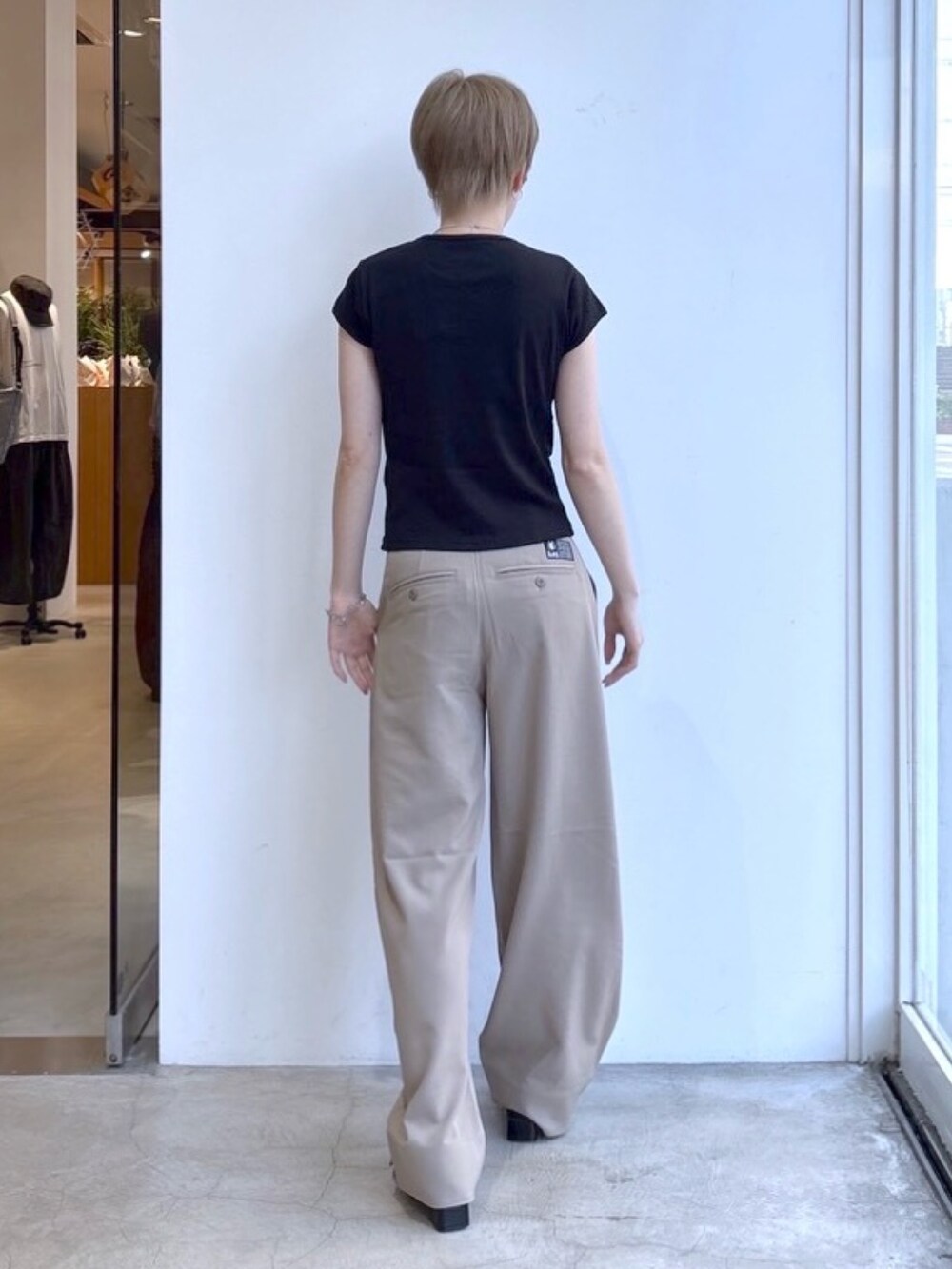 ベージュ系のスラックス、ブラック系のTシャツ/カットソー、シルバー系のネックレスを着用したレディースの春コーディネートの2枚目の写真