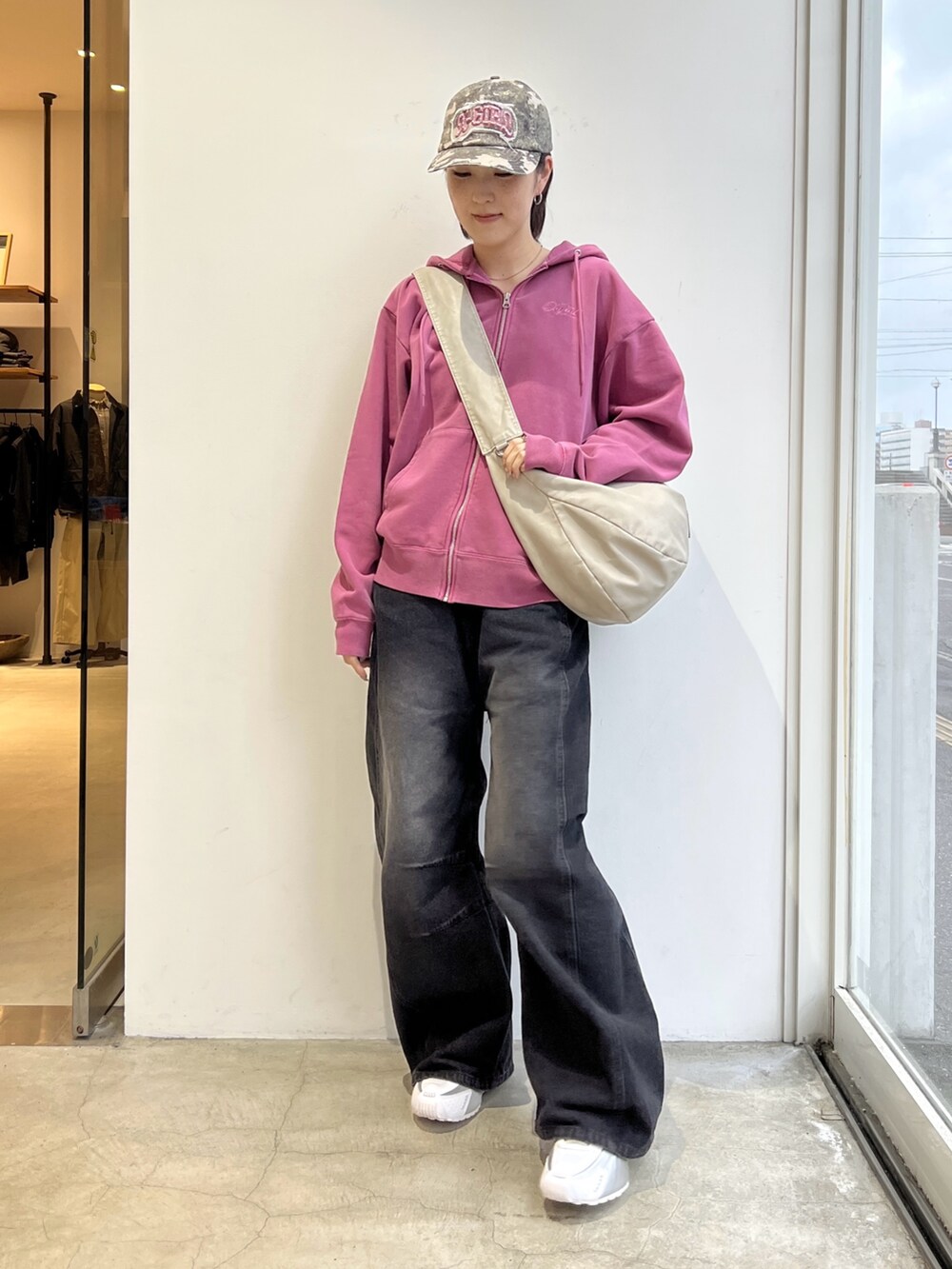 ブラック系のデニムパンツ、ホワイト系のショルダーバッグ、グリーン系のパーカーを着用したレディースの冬コーディネートの2枚目の写真