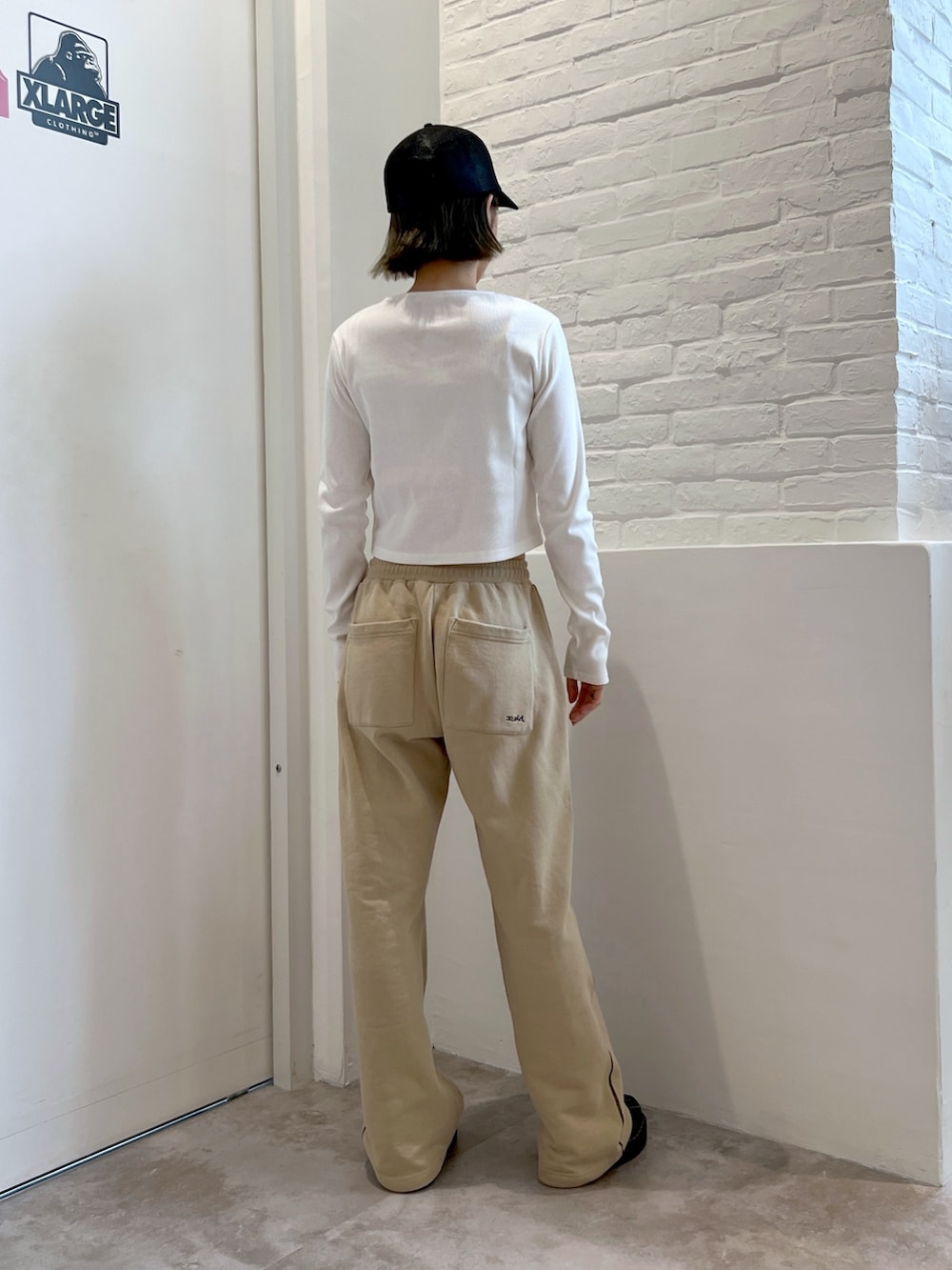 ベージュ系のスウェットパンツ、ホワイト系のカーディガン/ボレロ、ブラック系のキャップを着用したレディースの春コーディネートの2枚目の写真