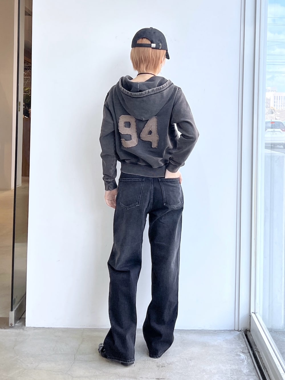 ブラック系のデニムパンツ、ブラック系のパーカー、ブラック系のキャップを着用したレディースの春コーディネートの2枚目の写真