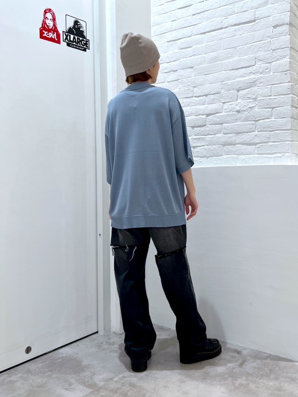 ブラック系のデニムパンツ、ブルー系のポロシャツ、ブラック系のニットキャップ/ビーニーを着用したレディースの春コーディネートの2枚目の写真