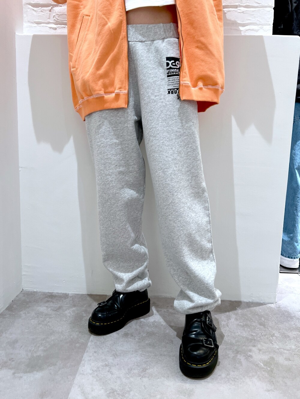 グレー系のスウェットパンツ、オレンジ系のスウェット、ホワイト系のパーカーを着用したレディースの春コーディネートの4枚目の写真