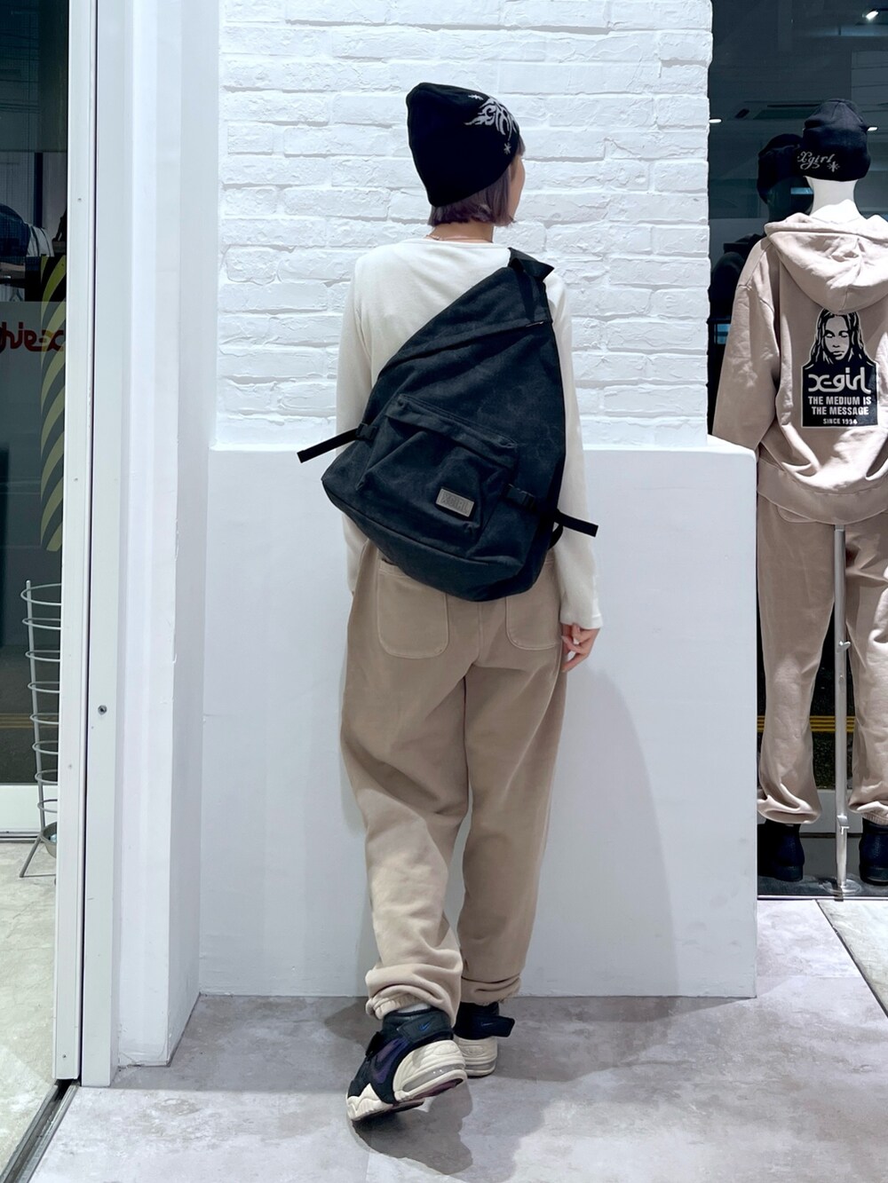 ベージュ系のスウェットパンツ、ホワイト系のTシャツ/カットソー、ブラック系のバックパック/リュックを着用したレディースの冬コーディネートの2枚目の写真