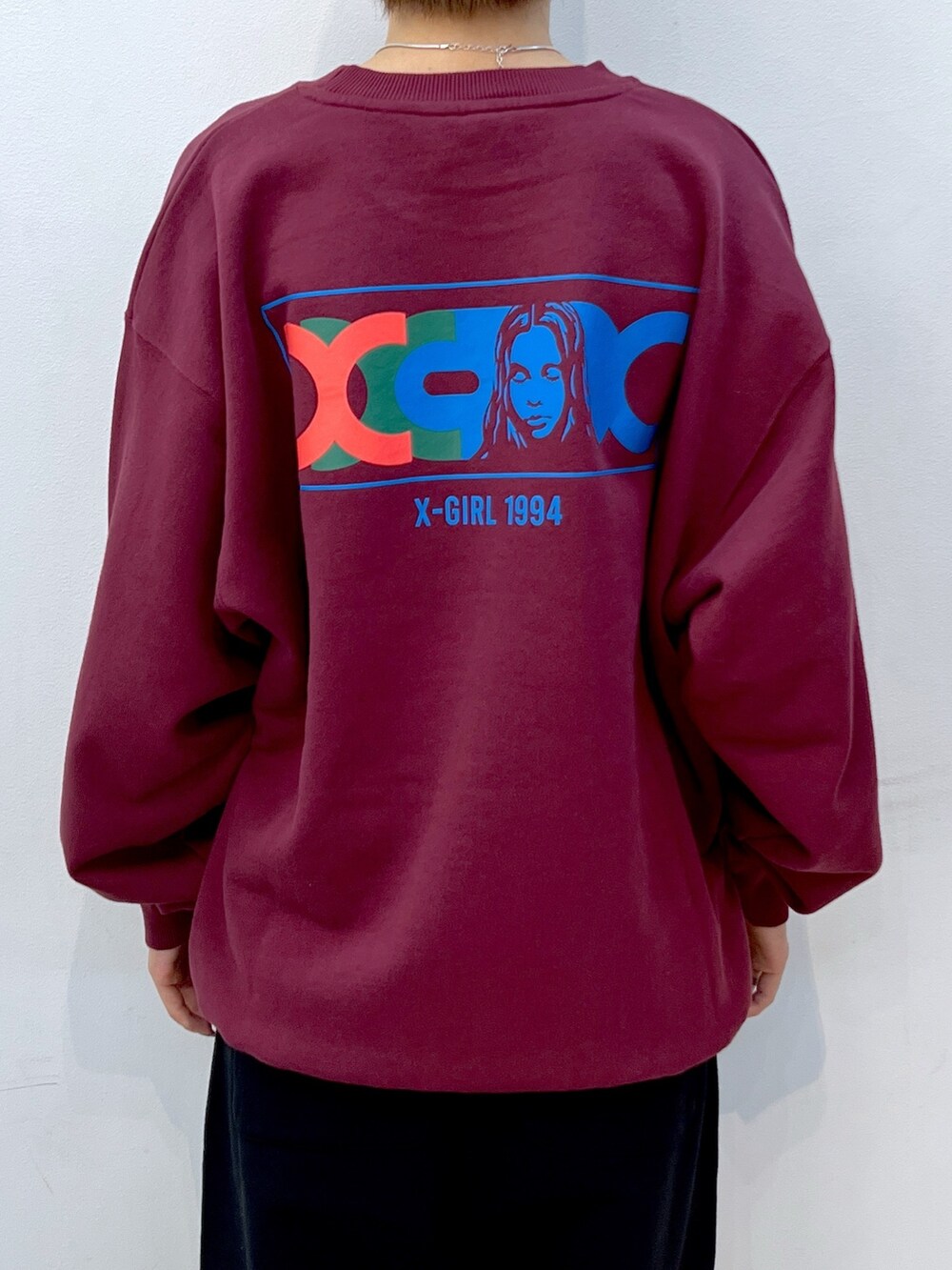 レッド系のスウェット、ブラック系のスウェットパンツ、ブラック系のスニーカーを着用したレディースの秋コーディネートの4枚目の写真