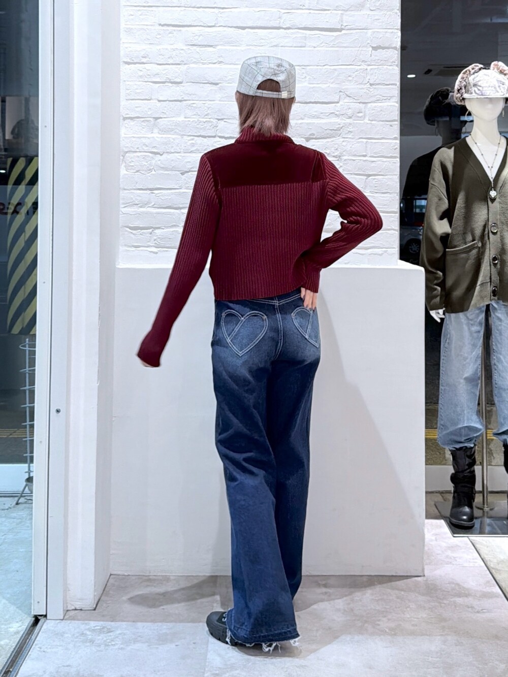 ブルー系のデニムパンツ、レッド系のニット/セーター、ブラック系のキャップを着用したレディースの秋コーディネートの2枚目の写真