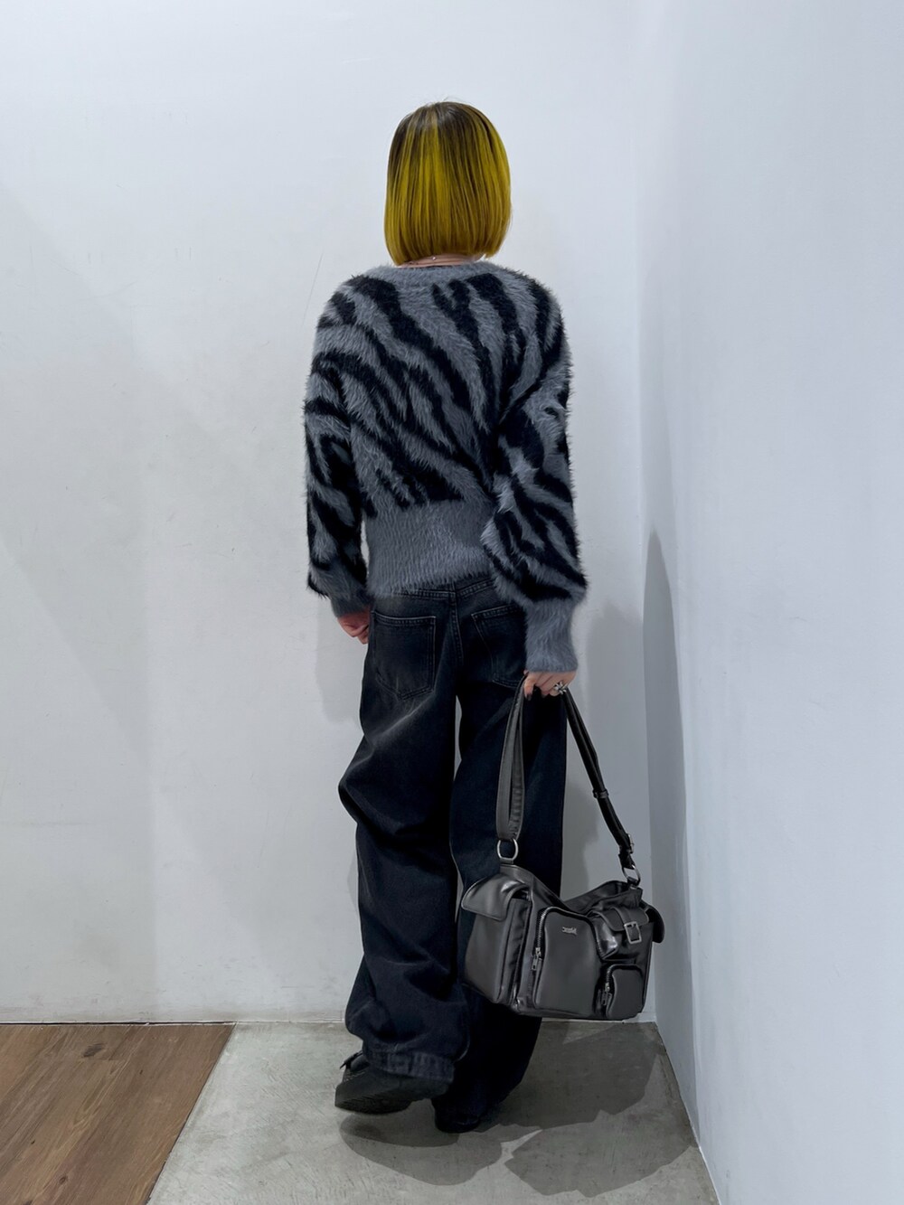 ブラック系のデニムパンツ、グレー系のハンドバッグ、グレー系のニット/セーターを着用したレディースの秋コーディネートの2枚目の写真