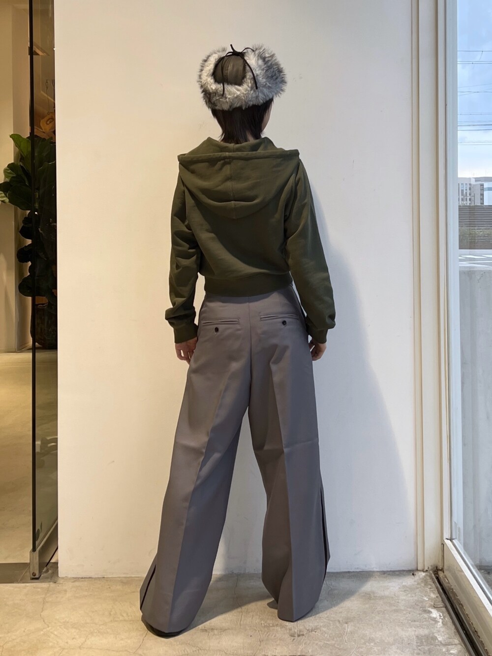 グレー系のスラックス、グリーン系のパーカー、ブラック系のキャップを着用したレディースの秋コーディネートの3枚目の写真