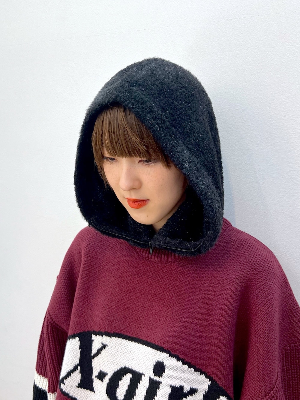 レッド系のニット/セーター、ブラック系のスウェットパンツ、ベージュ系のハンドバッグを着用したレディースの冬コーディネートの6枚目の写真