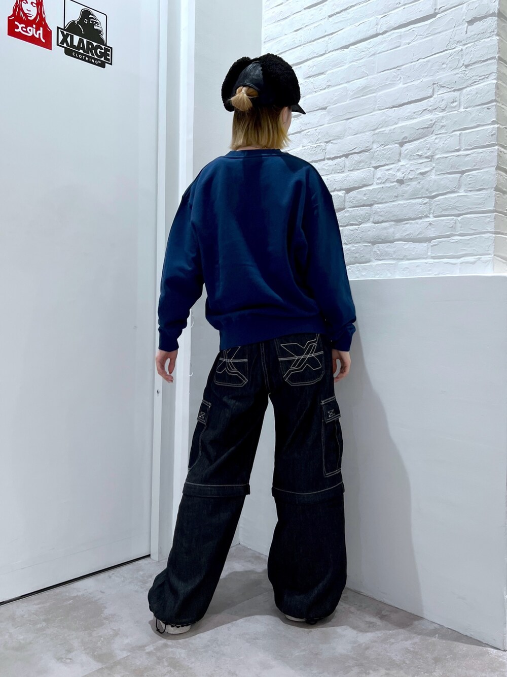 ブラック系のデニムパンツ、ブルー系のスウェット、ブラック系のキャップを着用したレディースの秋コーディネートの2枚目の写真