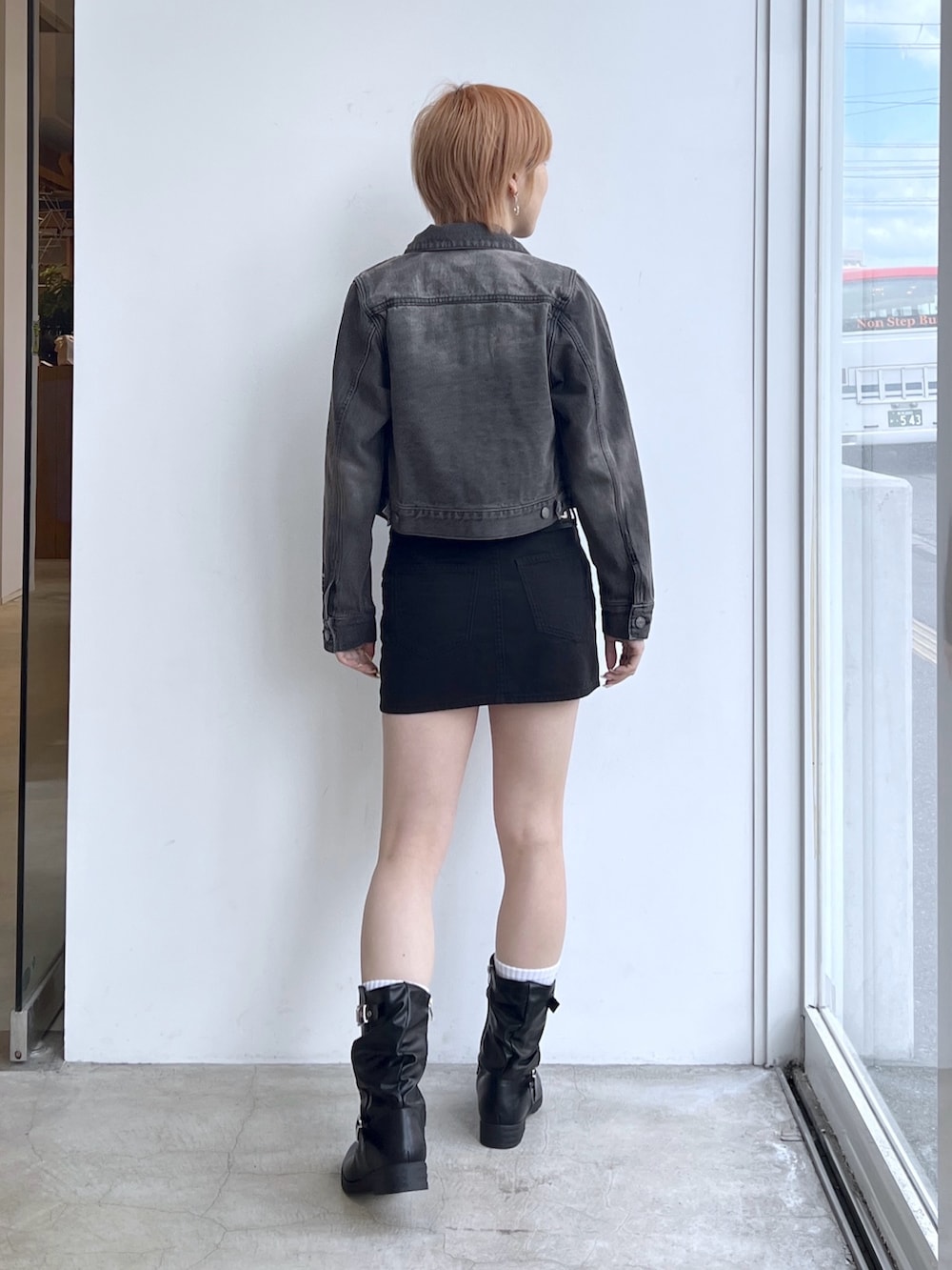 ブラック系のスカート、レッド系のTシャツ/カットソー、ブラック系のデニムジャケットを着用したレディースの春コーディネートの2枚目の写真