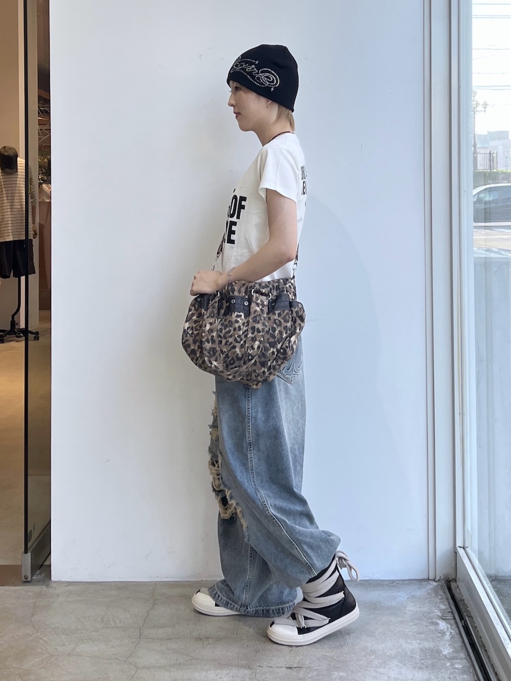 ブルー系のデニムパンツ、ベージュ系のショルダーバッグ、ホワイト系のTシャツ/カットソーを着用したレディースの夏コーディネートの2枚目の写真