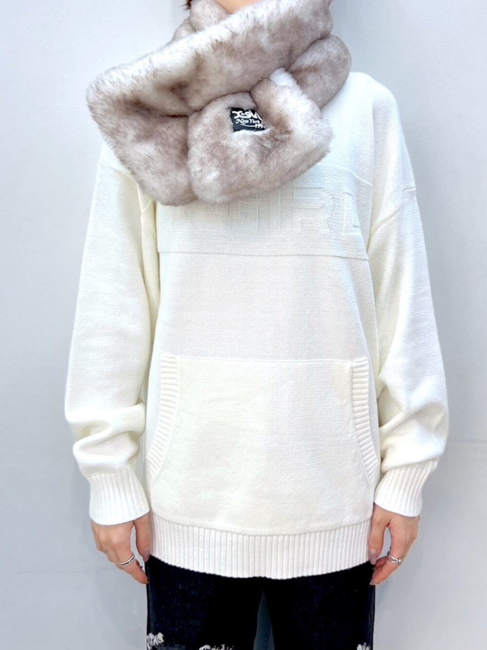ブラック系のデニムパンツ、ピンク系のショルダーバッグ、ホワイト系のニット/セーターを着用したレディースの冬コーディネートの3枚目の写真