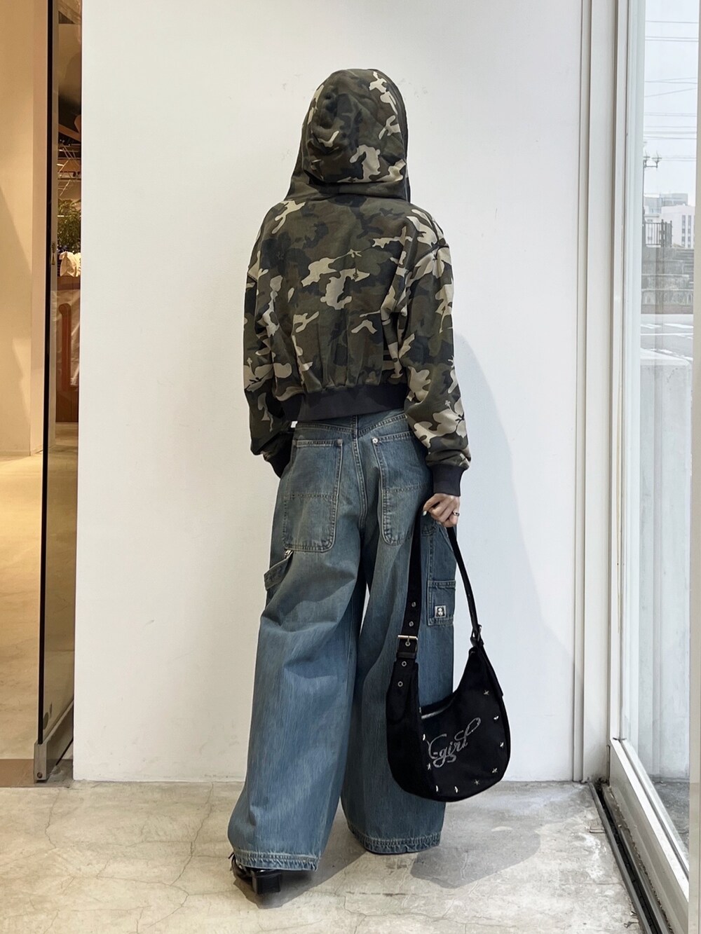 ブルー系のデニムパンツ、ブラック系のショルダーバッグ、ホワイト系のタンクトップを着用したレディースの春コーディネートの2枚目の写真