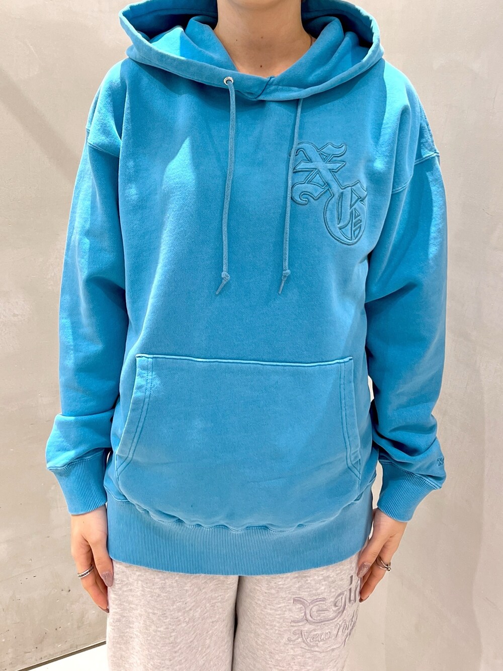 ブルー系のパーカー、ブラック系のショルダーバッグ、グレー系のスウェットパンツを着用したレディースの秋コーディネートの3枚目の写真