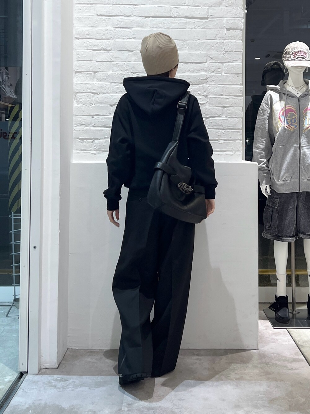 ブラック系のスラックス、ブラック系のショルダーバッグ、ブラック系のパーカーを着用したレディースの冬コーディネートの3枚目の写真