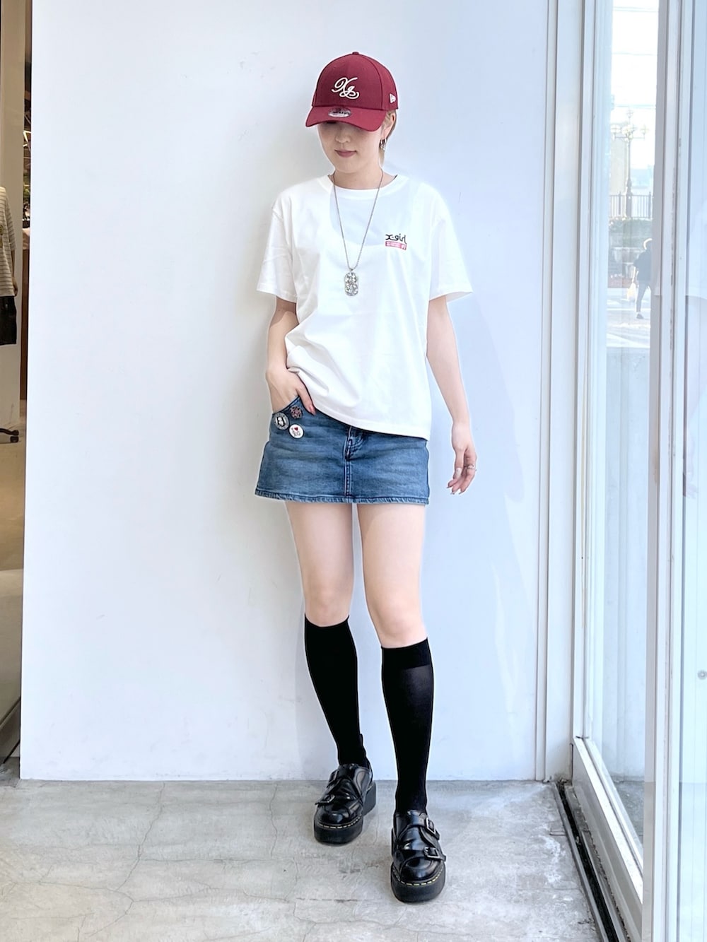 ブルー系のデニムスカート、ホワイト系のTシャツ/カットソー、レッド系のキャップを着用したレディースの夏コーディネートの2枚目の写真