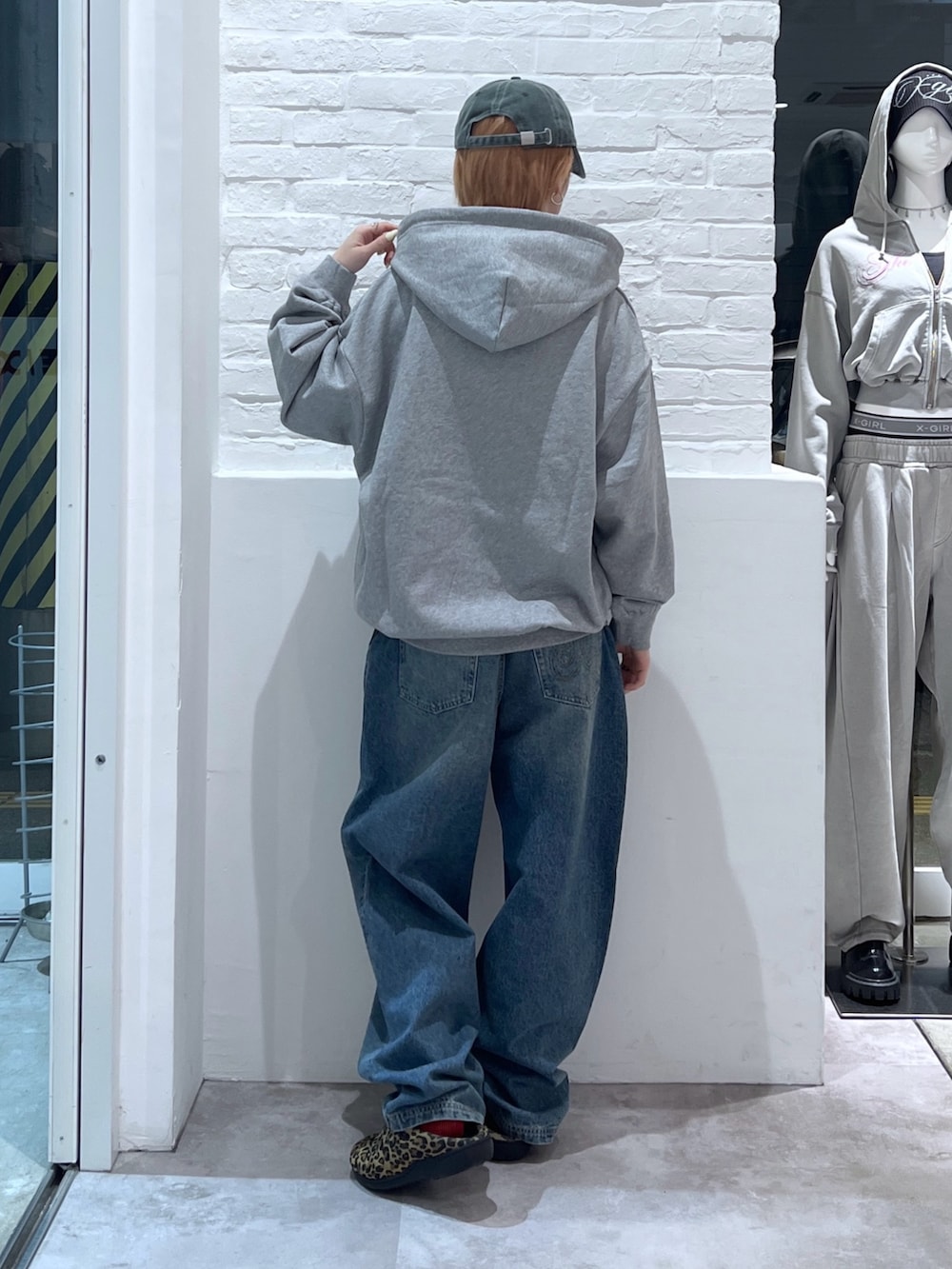 ブルー系のデニムパンツ、グレー系のパーカー、グリーン系のキャップを着用したレディースの春コーディネートの2枚目の写真