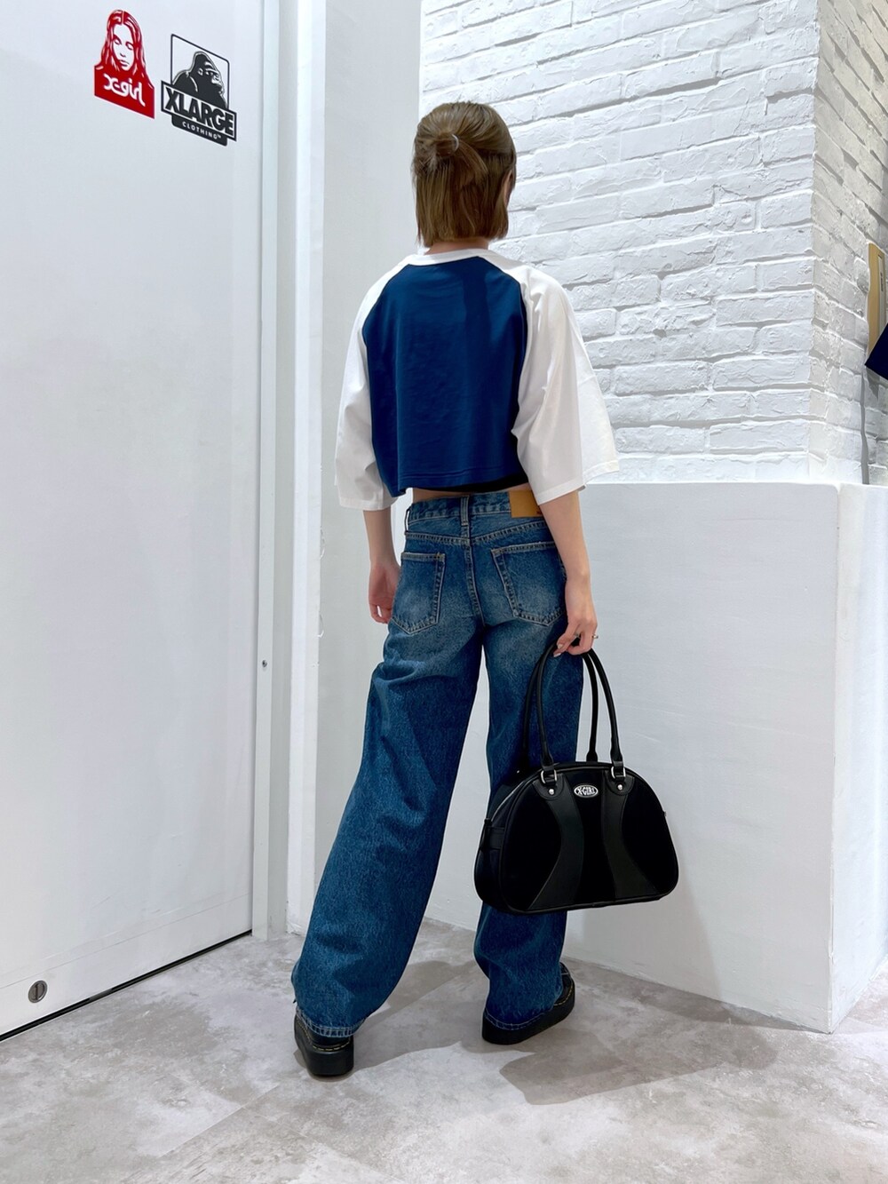 ブルー系のデニムパンツ、ブラック系のハンドバッグ、ブルー系のTシャツ/カットソーを着用したレディースの春コーディネートの2枚目の写真