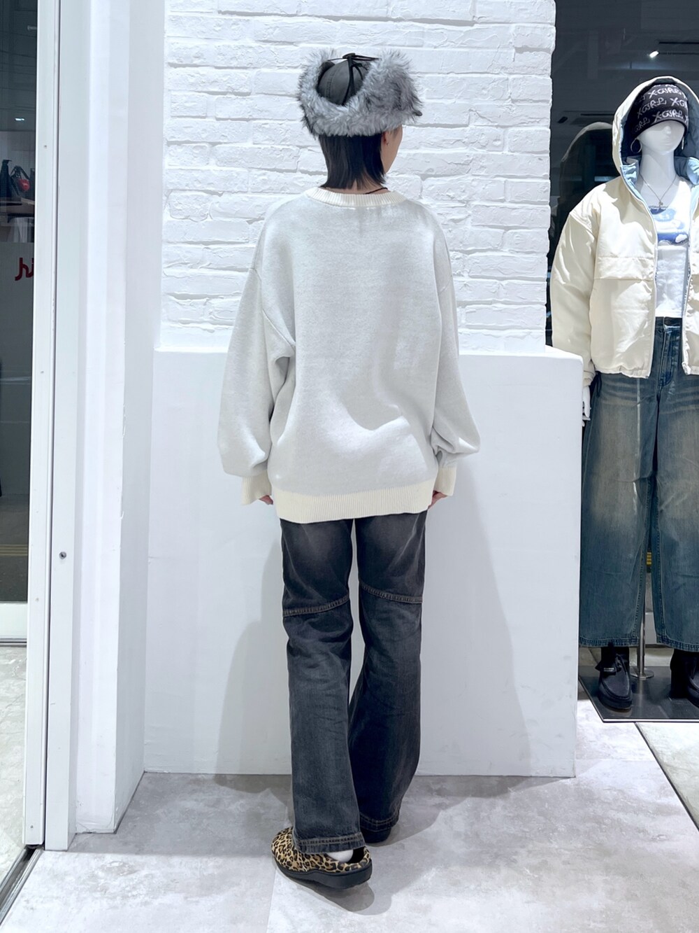 ブラック系のデニムパンツ、ホワイト系のニット/セーター、ブラック系のキャップを着用したレディースの秋コーディネートの2枚目の写真