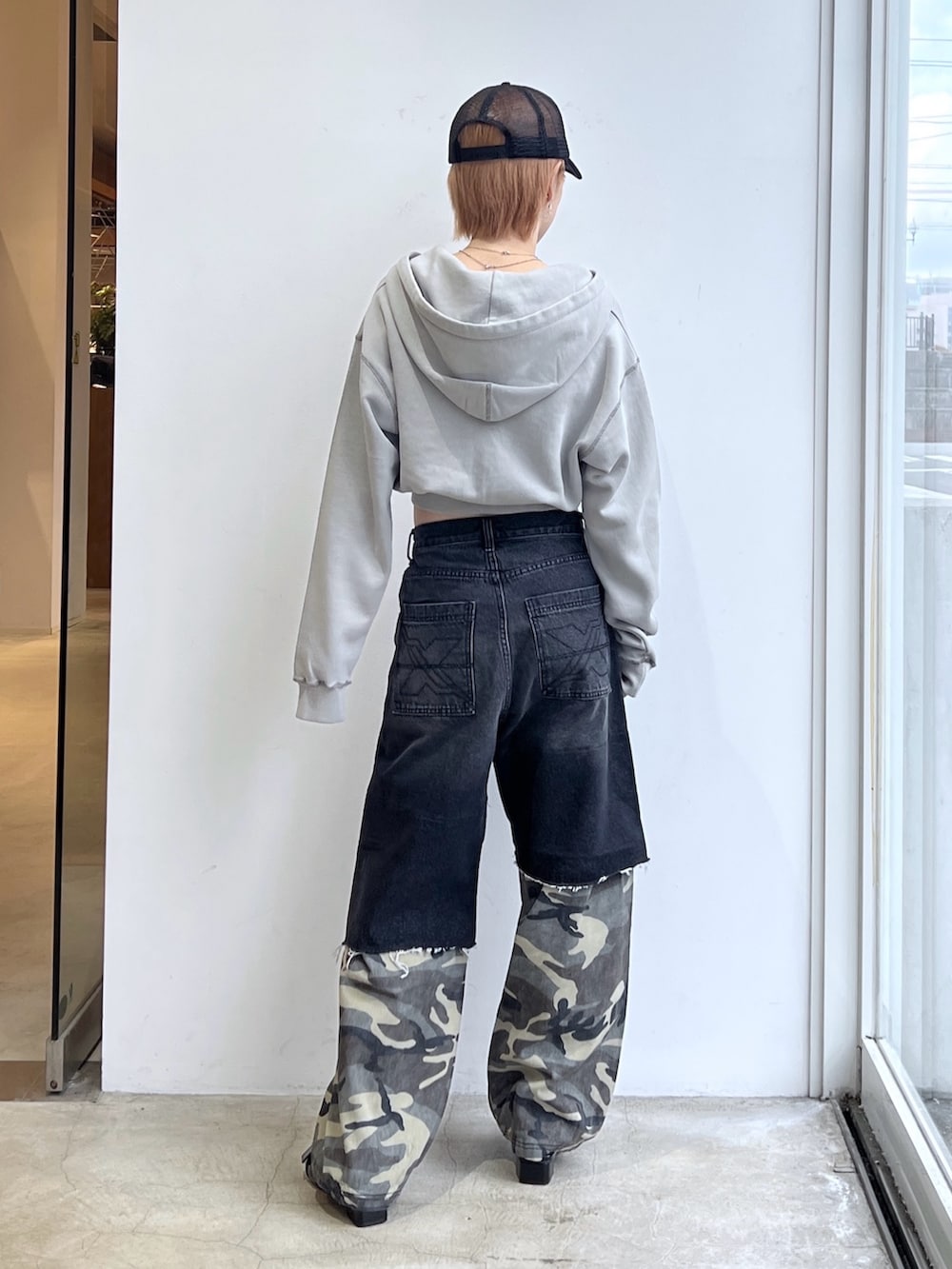 ブラック系のデニムパンツ、グレー系のパーカー、ブラック系のキャップを着用したレディースの春コーディネートの2枚目の写真