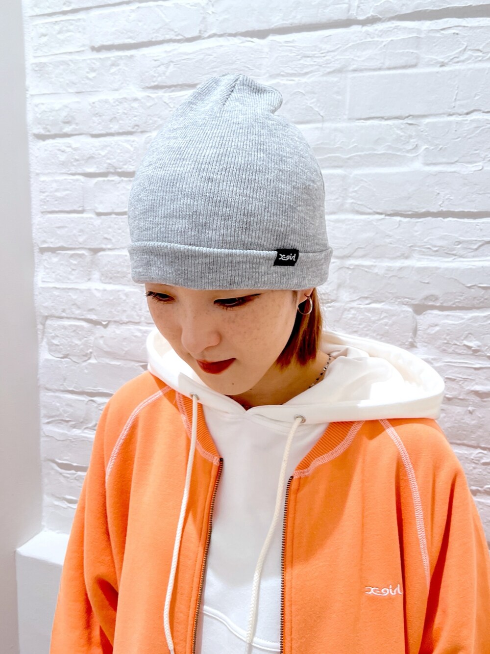 グレー系のスウェットパンツ、オレンジ系のスウェット、ホワイト系のパーカーを着用したレディースの春コーディネートの6枚目の写真